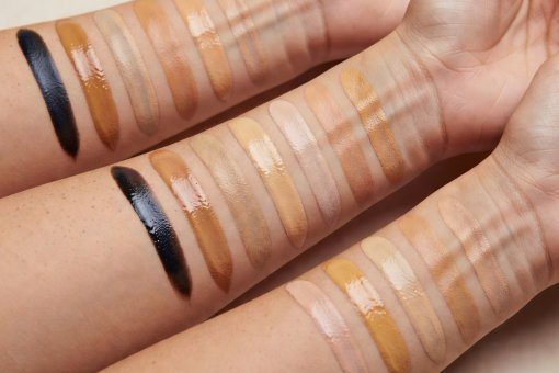 Macro view of multiple foundation test lines on diverse skin complexions showing color interaction